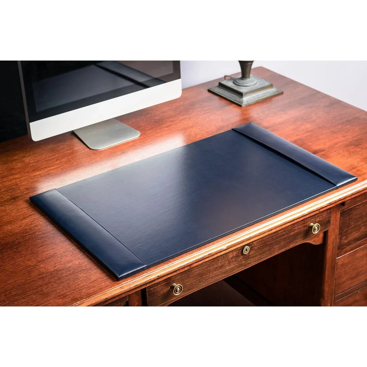 Navy blue bonded leather desk pad on wooden office desk with monitor