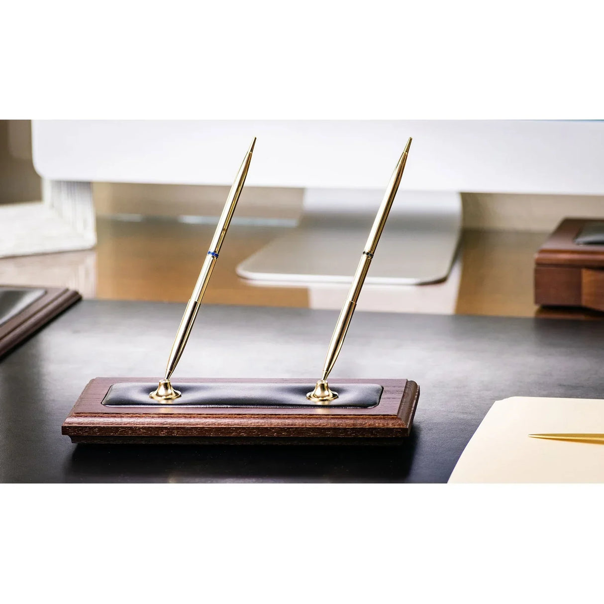 Walnut and black leather double pen stand with two gold pens on office desk