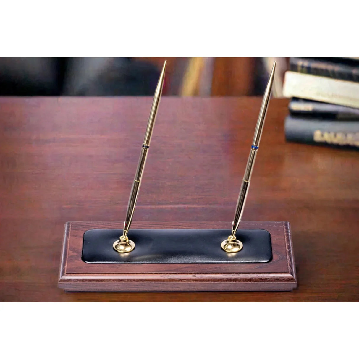 Walnut and black leather double pen stand with two gold pens on a wooden desk