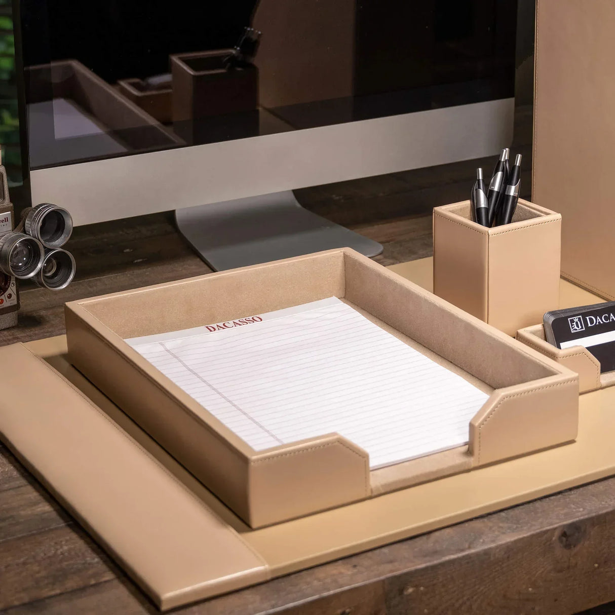 White leather letter tray on an organized office desk with pens and stationery