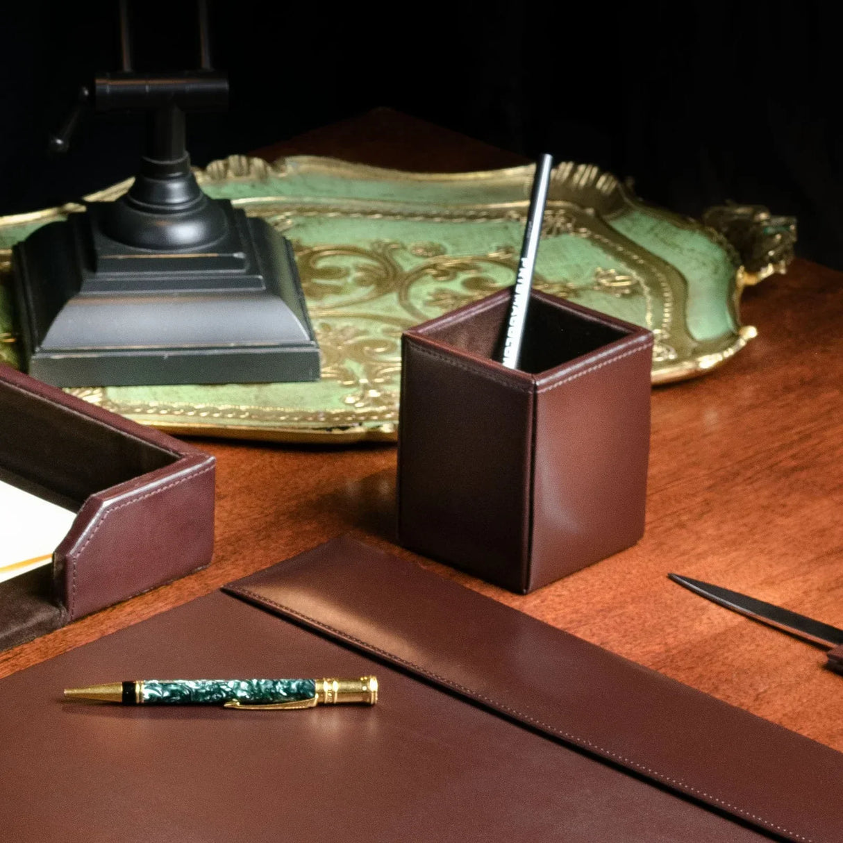 Dark brown bonded leather pencil cup on a wooden desk with office accessories