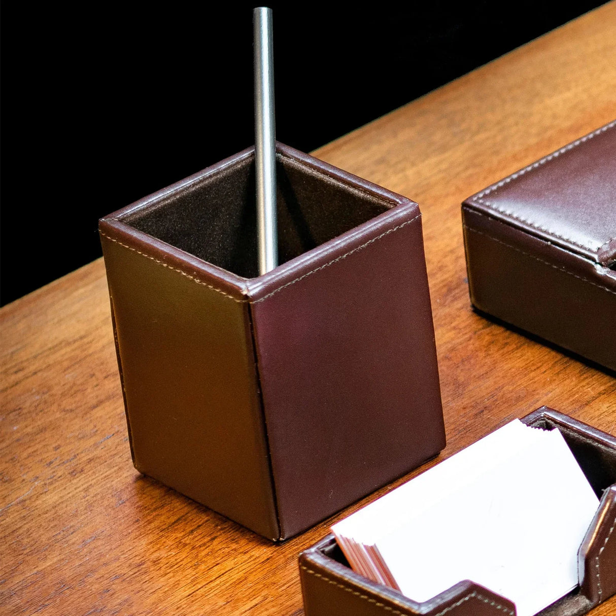 Dark brown bonded leather pencil cup on wooden desk with pen and organizer accessories