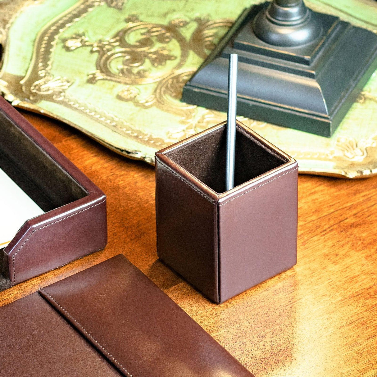 Dark brown bonded leather pencil cup on wooden desk with office accessories