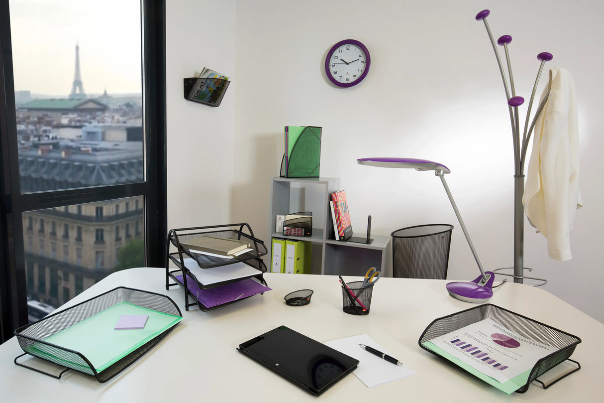Modern office workspace with mesh organizers, desk lamp, clock, and Eiffel Tower view