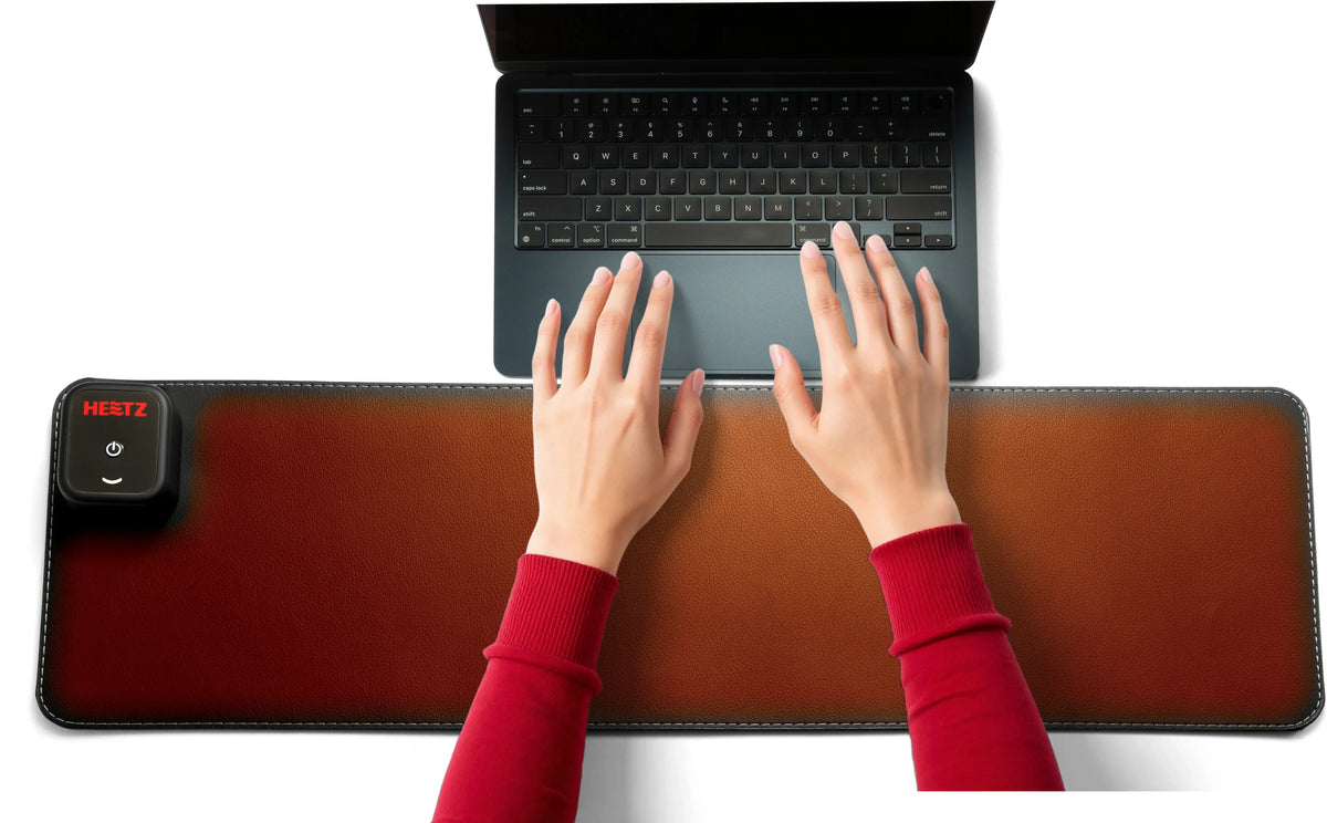Hands typing on a laptop over a brown Victor® Heetz heated grounding desk pad.