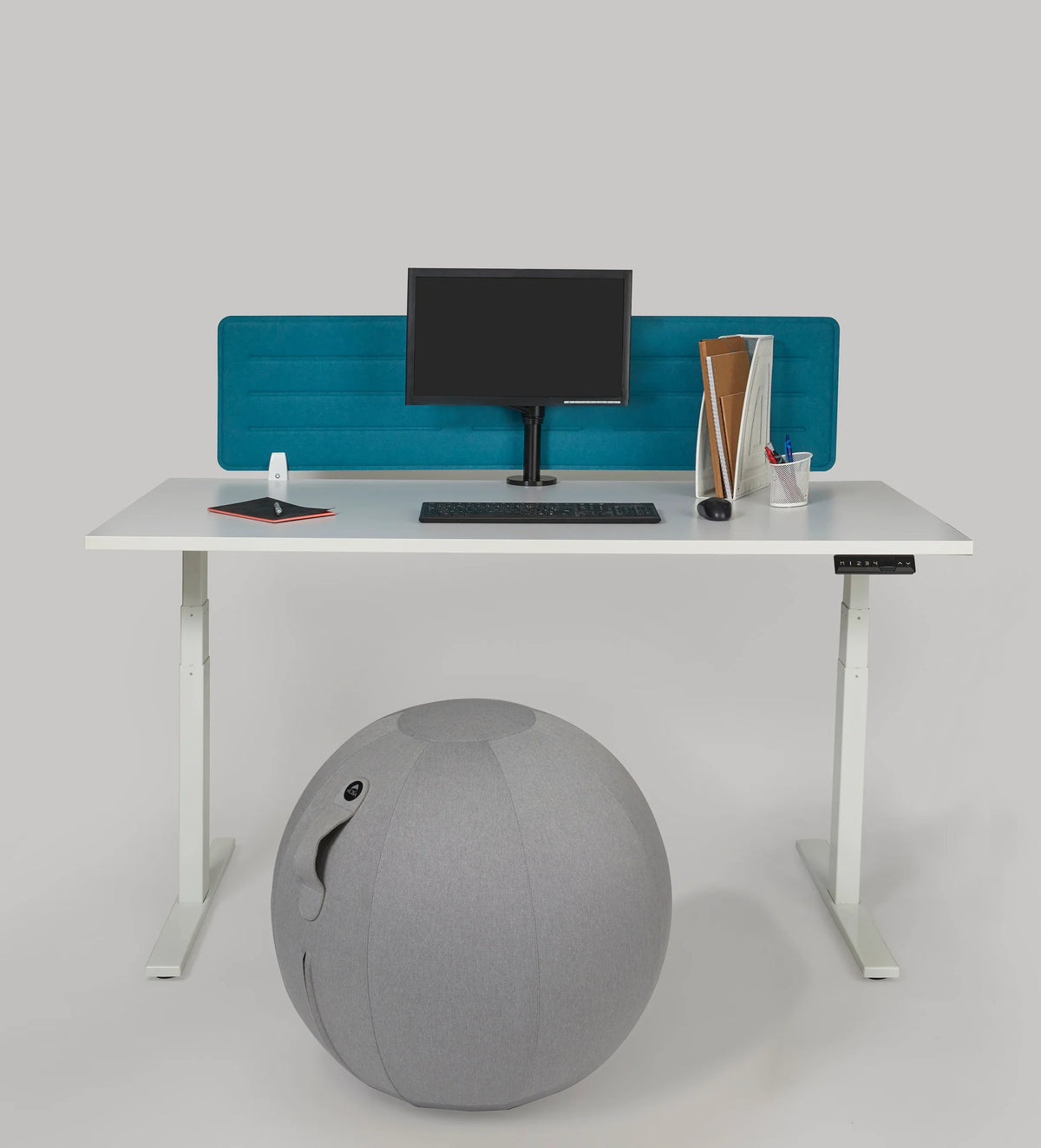 Grey Alba MoveHop Ergonomic Seat Ball under a white standing desk in an office setting.