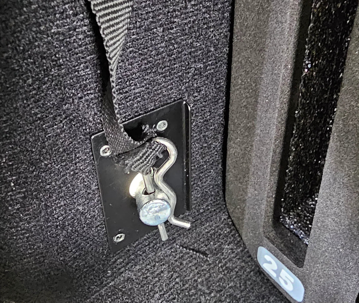 Close-up of a cotter key securing a black strap to a metal anchor plate inside of the Vaultz cell phone locker