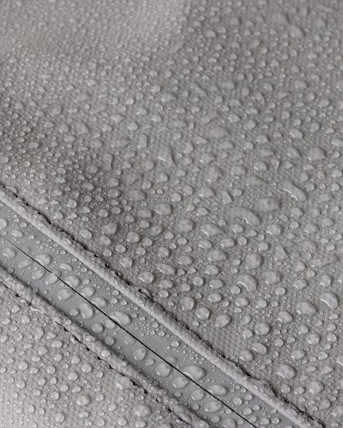 Close-up of water droplets on a gray water-resistant fabric surface with zipper