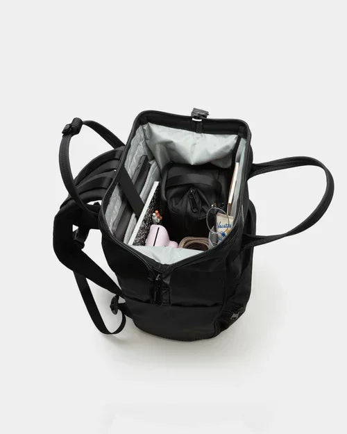 Black backpack with organized compartments holding notebooks, pens, and office supplies for school or work