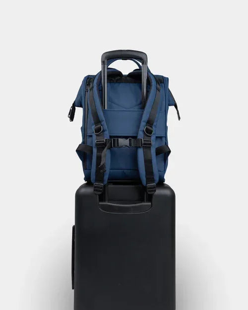 Blue backpack with black straps mounted on black rolling suitcase for travel or commute