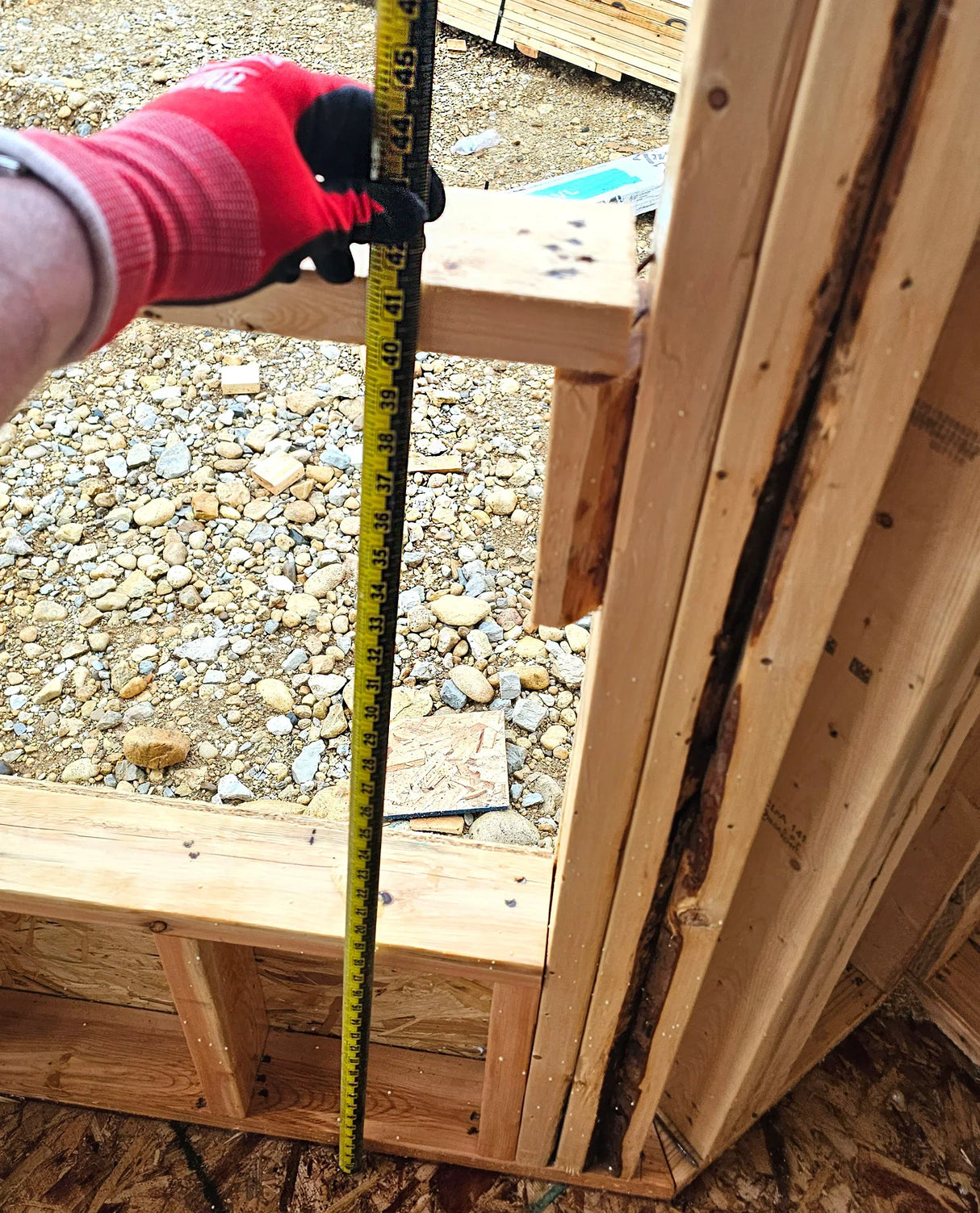 Measuring wooden frame with tape measure on construction site