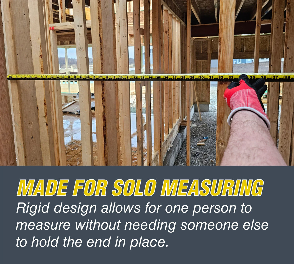 Hand holding rigid measuring tape for solo use in wooden framing construction