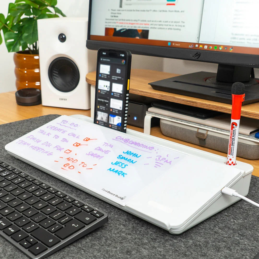 White desktop dry erase board with wireless charging, marker, and smartphone stand on office desk