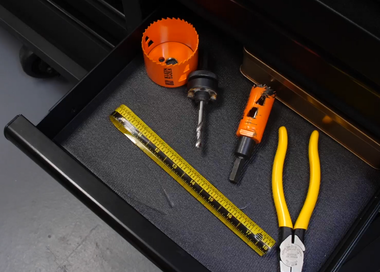 Tools including a drill bit, pliers, and a Zip Stick ruler on a black drawer interior.