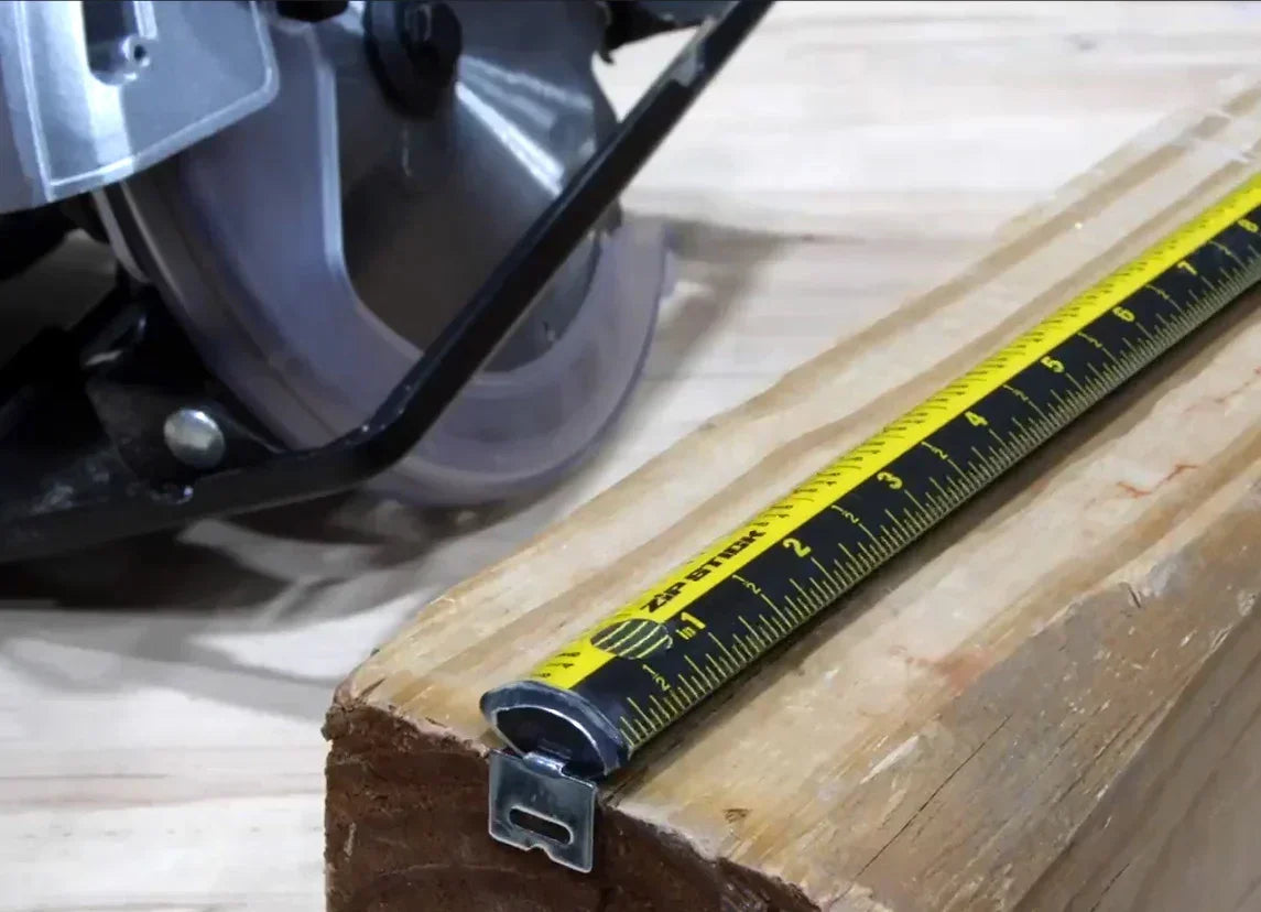 Yellow tape measure on wooden plank beside circular saw, measuring for precise cuts