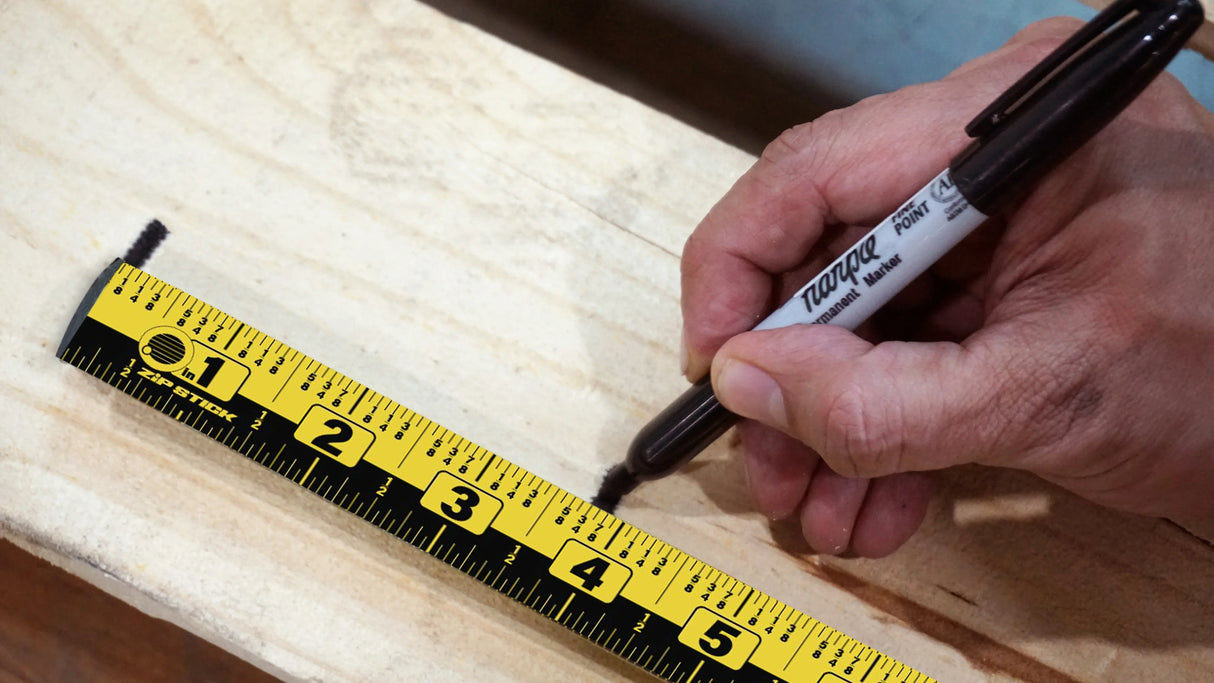 Hand marking wood with Sharpie marker and yellow measuring tape for precise cuts