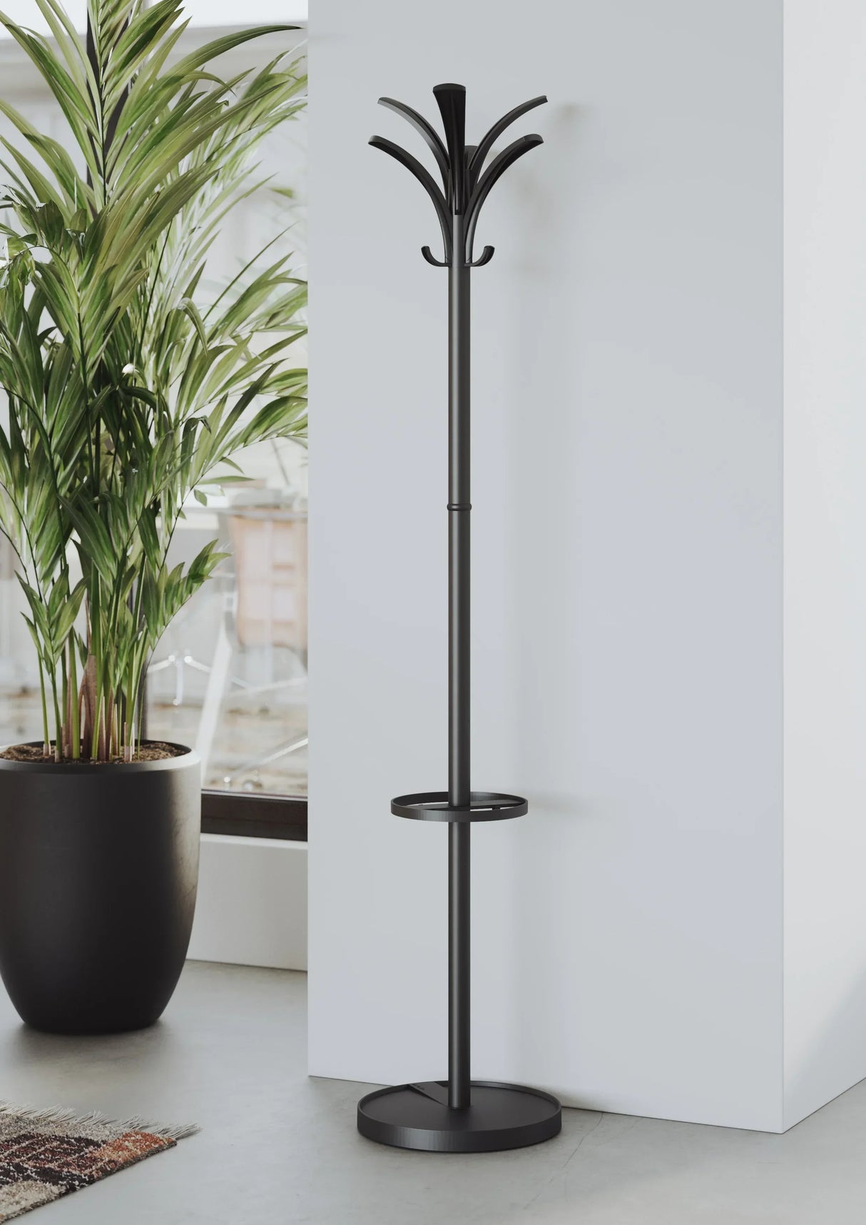Modern black coat rack with umbrella holder beside potted plant in minimalist office