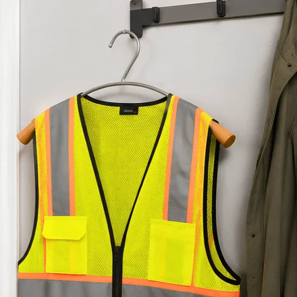 A high-visibility safety vest hanging on an Alba metal and wood clothes hanger.