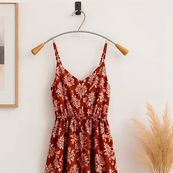 Alba metal and wood clothes hanger holding a red floral dress against a white wall