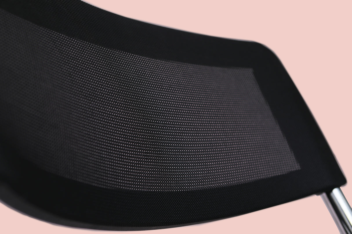 Close-up of black mesh folding chair backrest with chrome frame on pink background