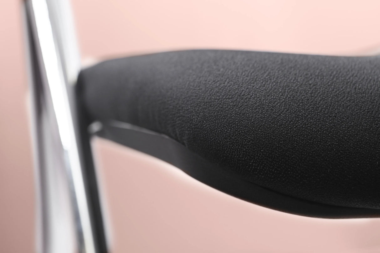 Close-up of a black mesh folding chair seat with chrome frame on a pink background
