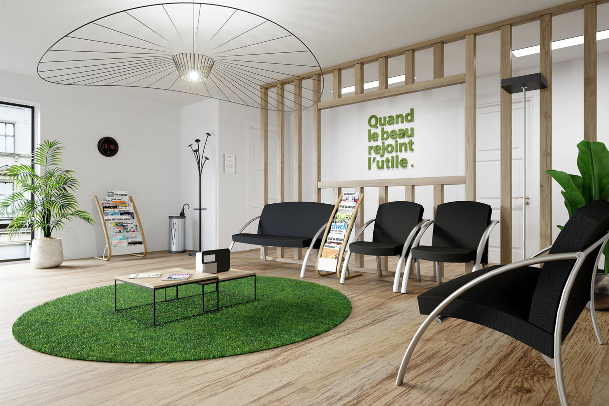 Modern waiting room with black chairs, floor display stands, green rug, plants, and wall decor.