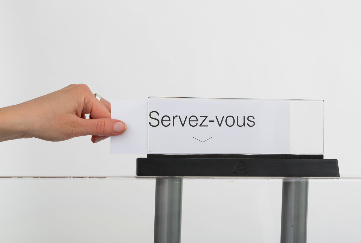 Hand placing card into clear acrylic display sign with Servez-vous text on a black base.