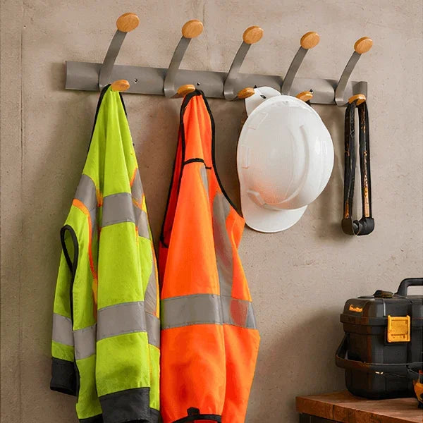 Alba wall mounted double peg rail holding safety vests, a hard hat, and a strap.