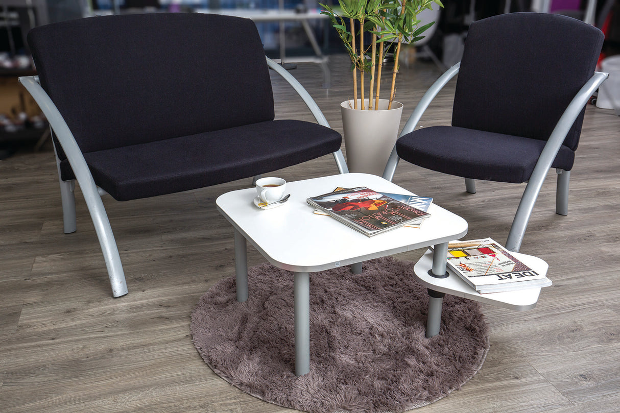 Modern white coffee table with rotating top and magazines in office lounge setting