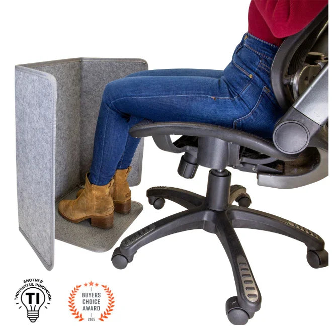 Person seated at desk using under-desk foot and leg heater, ergonomic home office accessory