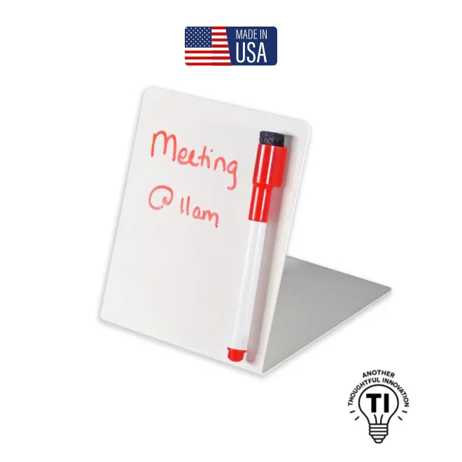 Angle view of small white magnetic dry erase board with red marker and handwritten meeting reminder