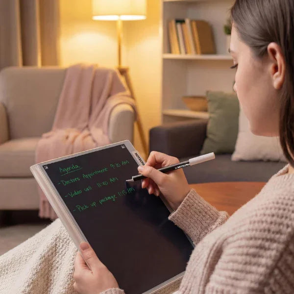 Person writing on a digital smart notebook with stylus in a cozy living room setting