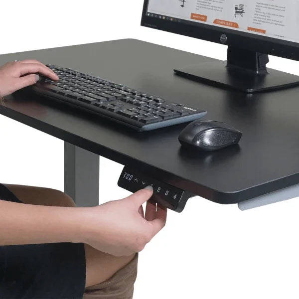 Person adjusting the height of a Victor® High Rise™ electric standing desk using the control panel