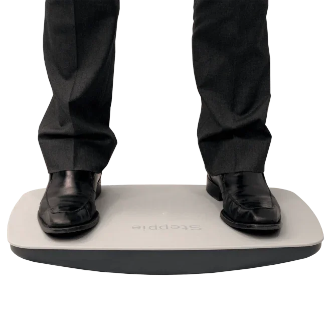 Man in dress shoes standing on Steppie balance board for office ergonomic support