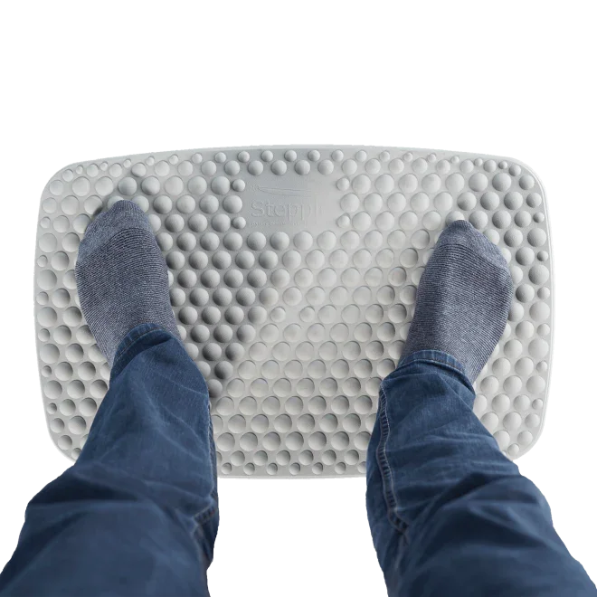 Feet in socks standing on a textured anti-fatigue standing desk mat for ergonomic comfort