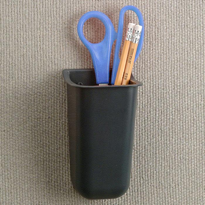 Wall-mounted black tool tube organizer holding blue scissors and pencils on fabric panel