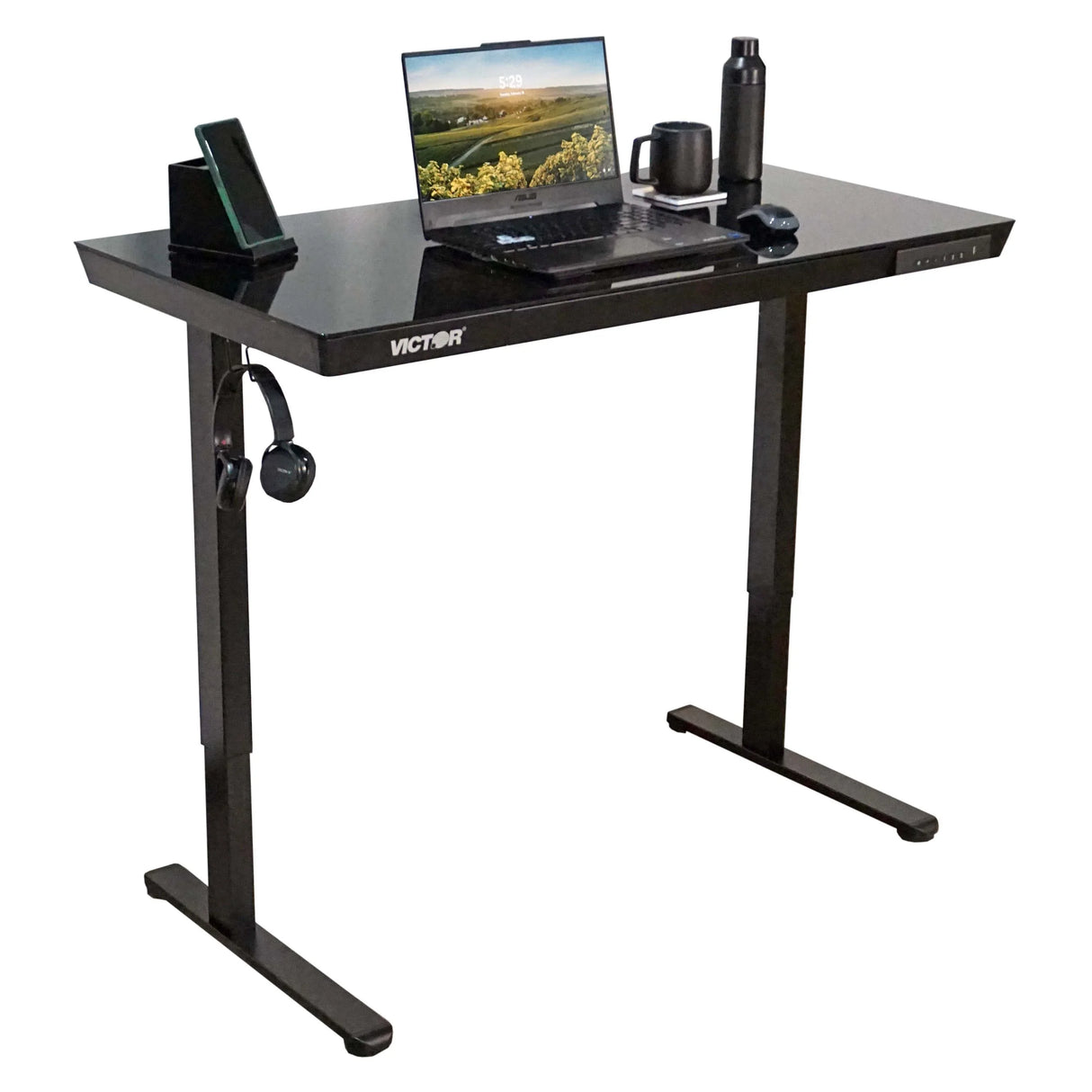 Electric glass-topped standing desk with laptop, mug, water bottle and accessories