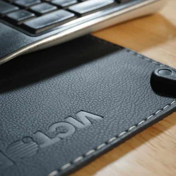 Close-up of a black leather Victor® grounding desk pad with embossed logo and stitching.