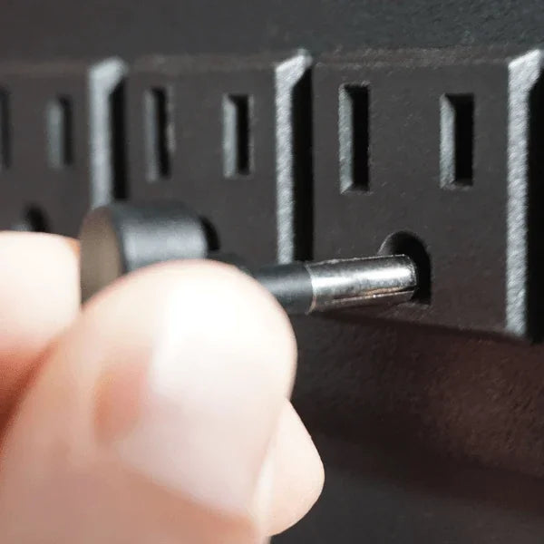 Close-up of a Victor® grounding desk pad plug being inserted into a power outlet ground hole.