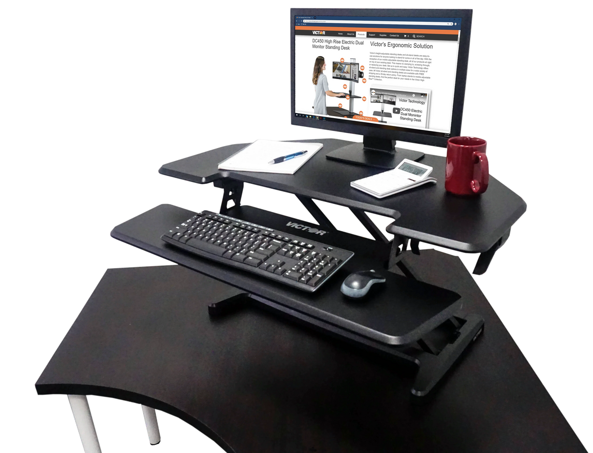 High-rise adjustable corner standing desk with keyboard tray, monitor, and office accessories