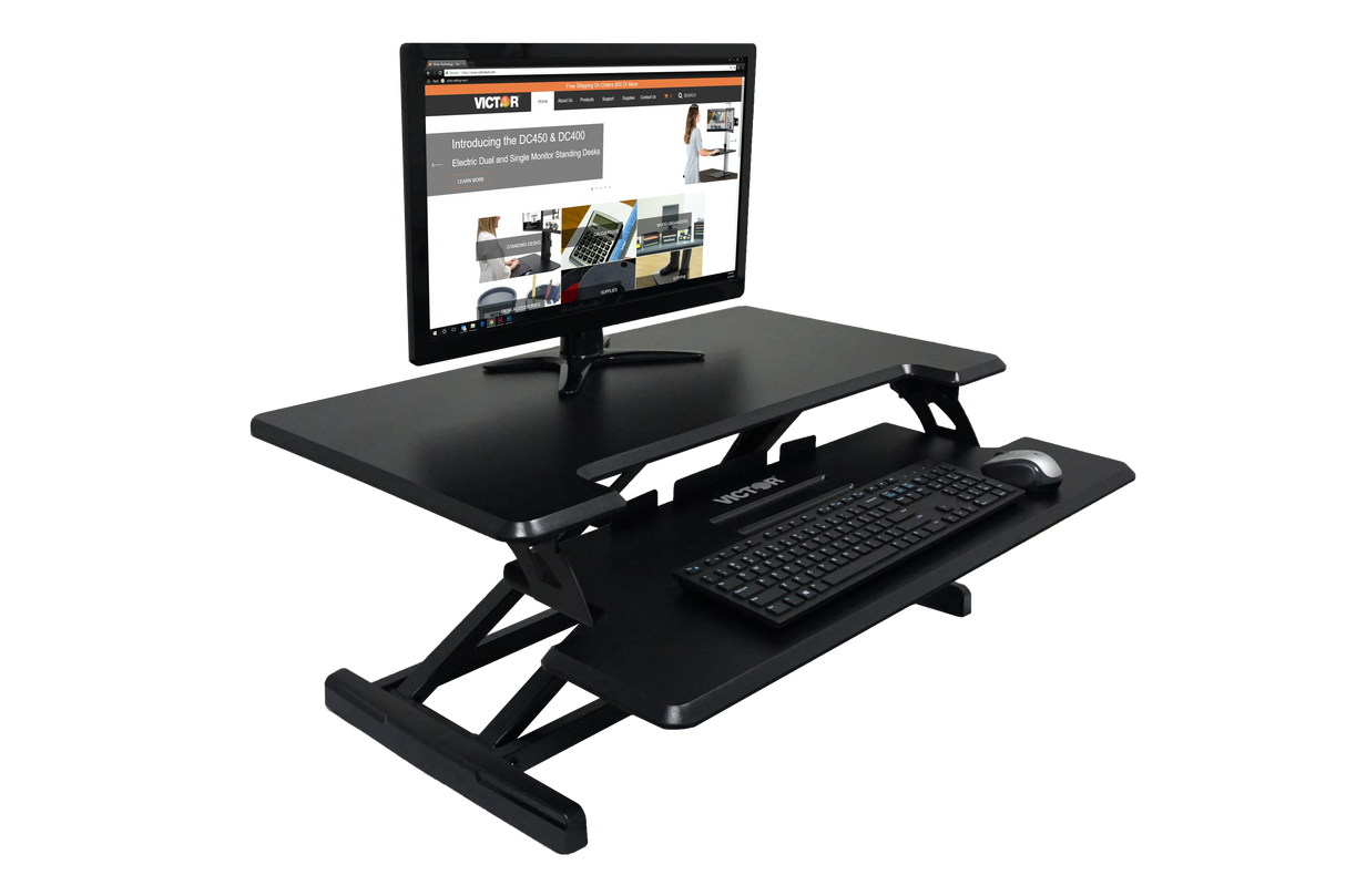 Adjustable height standing desk with monitor, keyboard, and mouse on black workstation
