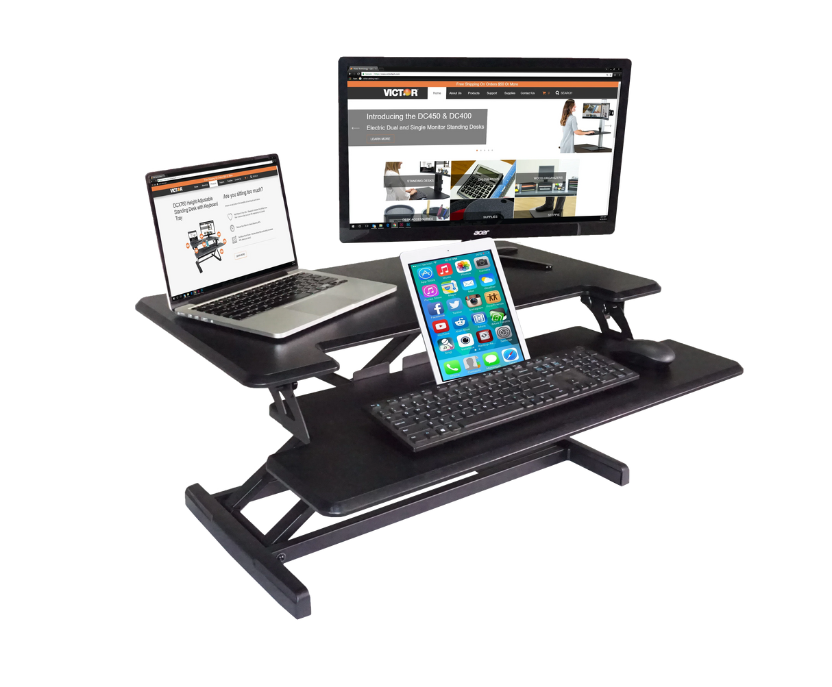 Adjustable height standing desk with monitor, laptop, tablet, keyboard, and mouse setup