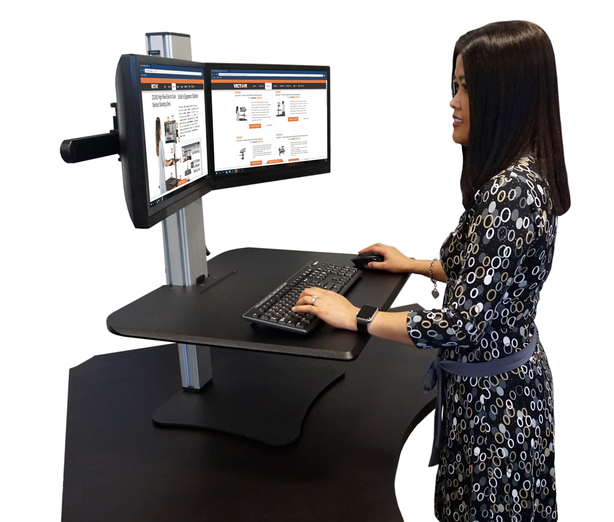 Woman using a high-rise dual monitor standing desk with keyboard and mouse