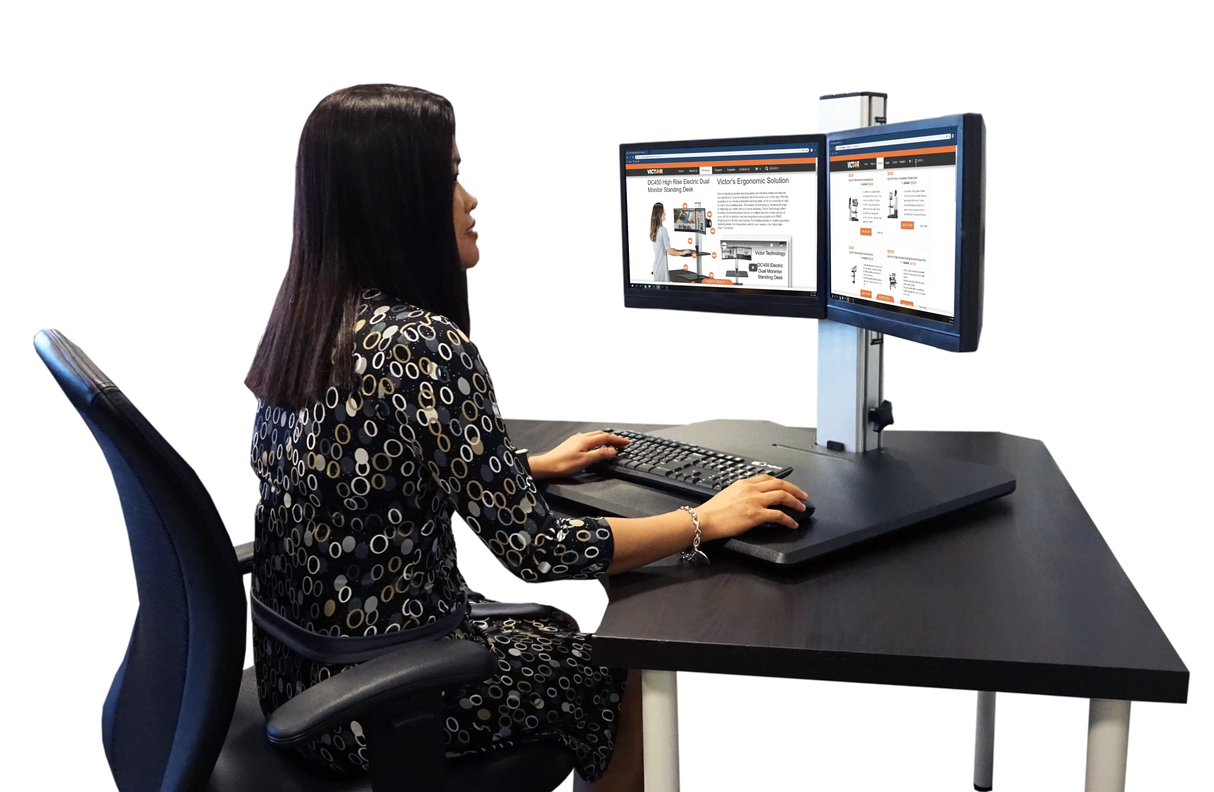 Woman working at a high-rise dual monitor standing desk with ergonomic setup in office