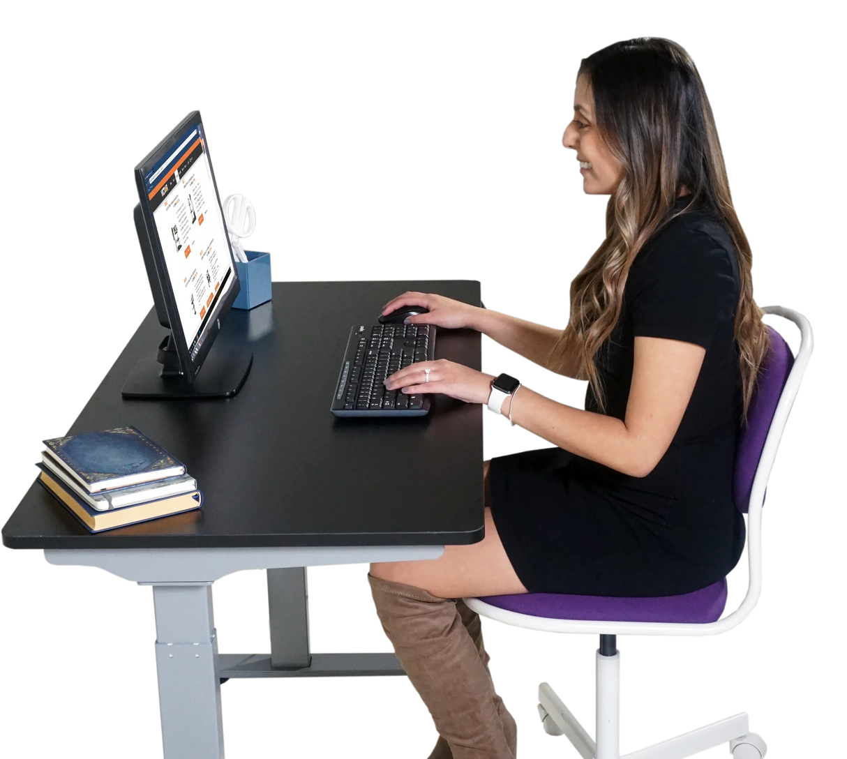 Woman working at a black electric adjustable height standing desk with computer and books
