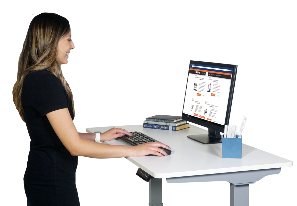 Woman working at a white electric height adjustable standing desk with monitor and keyboard