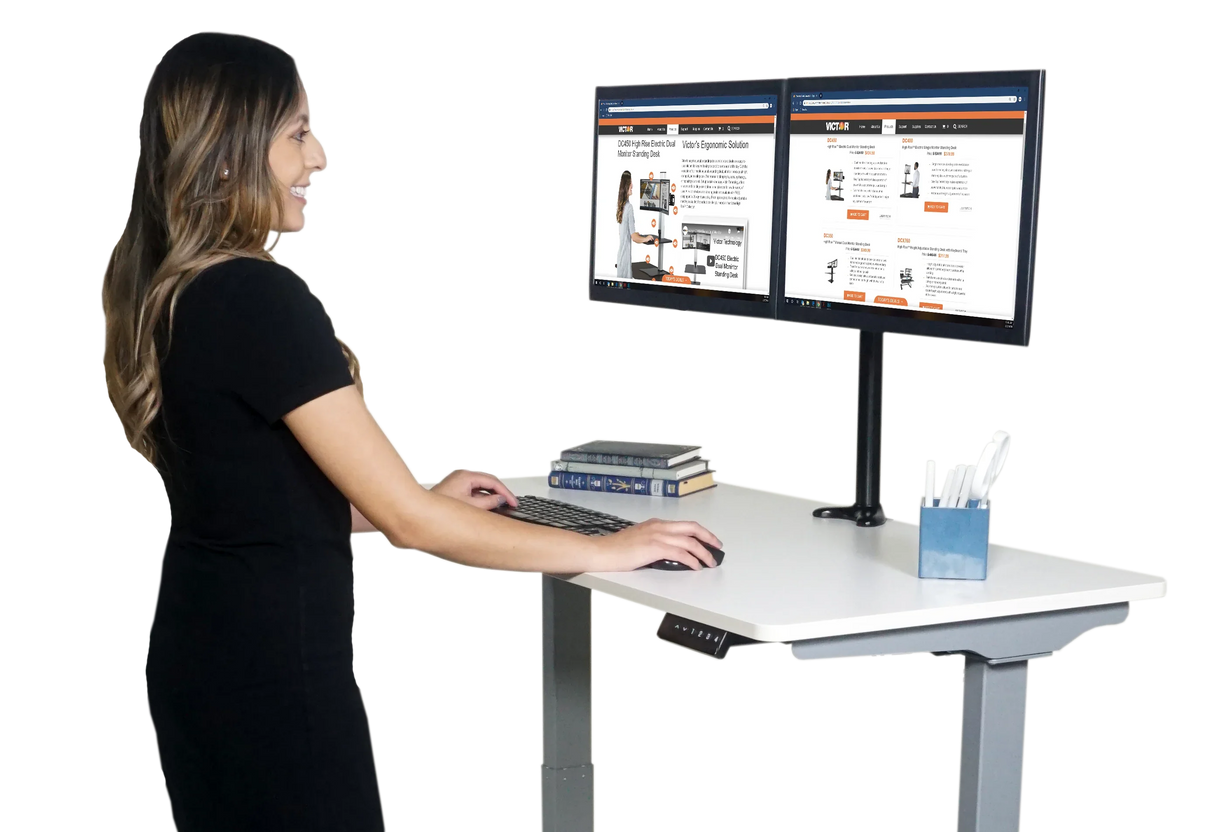 Woman working at an electric adjustable height standing desk with dual monitors