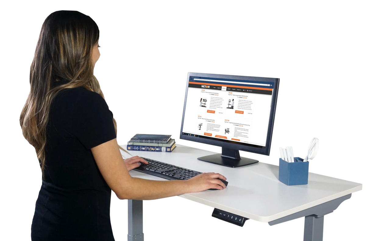 Woman working at an electric adjustable height standing desk with computer and office supplies