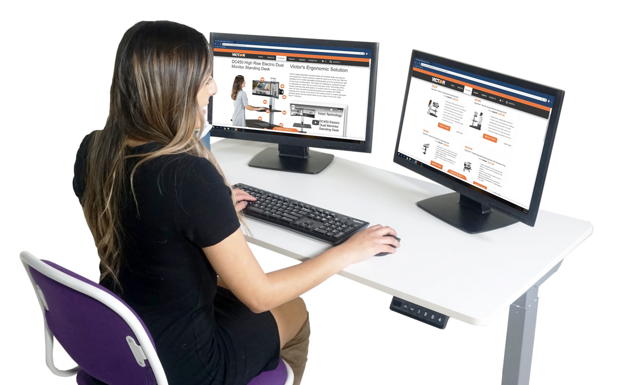 Woman working at white electric adjustable standing desk with dual monitors