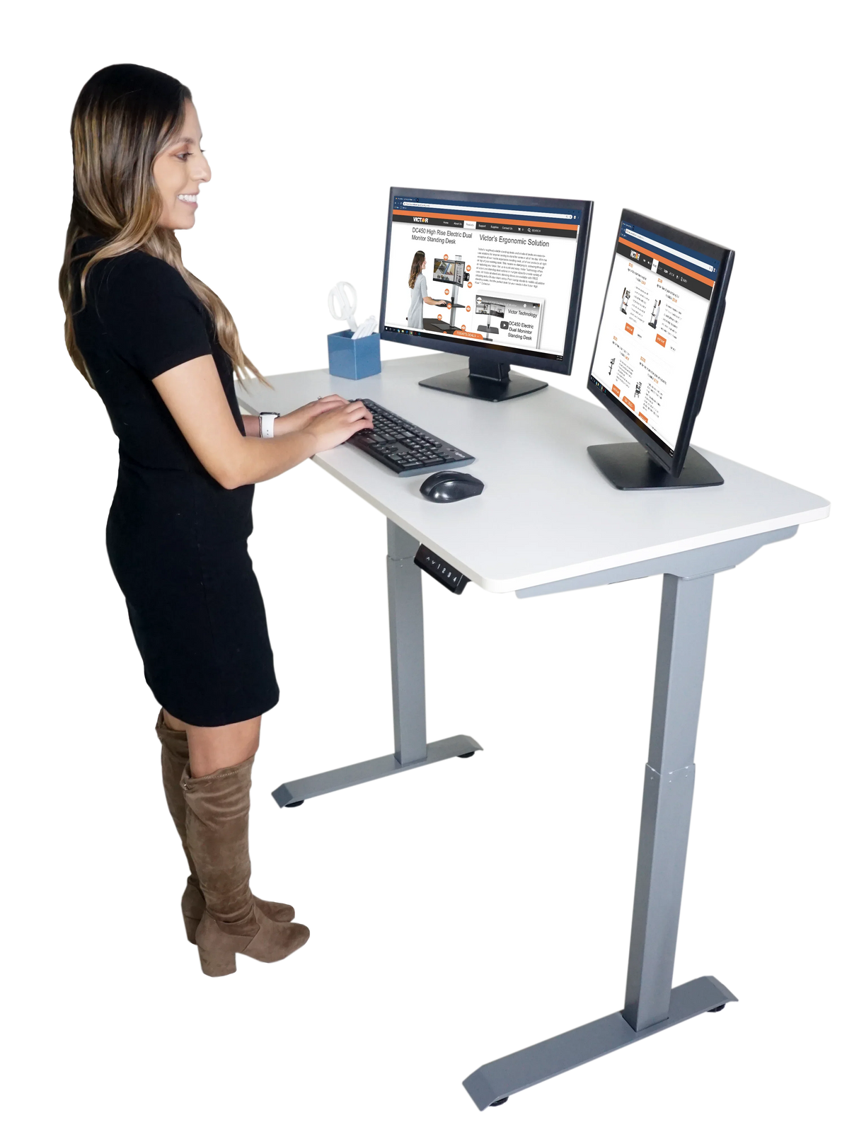Woman using dual monitors at high-rise electric adjustable standing desk in office setting
